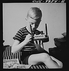 German refugee boy repairing a model of the SS Normandie which he made