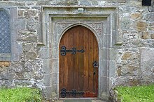 The north door, decorated with carvings and two heads Llanbedrgoch St Peters Church, Anglesey - door and carvings.jpg