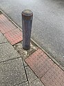 Wooden bollard painted grey, some paint is worn away