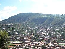 Panorama photograph showing houses in foreground, with Mount Kigali in the background