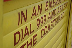 A sign on a beach in Whitstable, United Kingdom, advising readers to dial 999 and to request for the coastguard in the event of an emergency Sign for 999.jpg