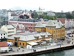 Blick auf eine am Wasser gelegene Stadt mit einem älteren, gelb gestrichenen Gebäude im Vordergrund