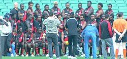 The Tiwi Bombers team line-up for a historic match against Rumbalara at the Melbourne Cricket Ground as a curtain raiser to the "Dreamtime at the 'G" game. The Bombers defeated their Victorian opponents by a massive margin, posting a near ground record score. Tiwi bombers.jpg