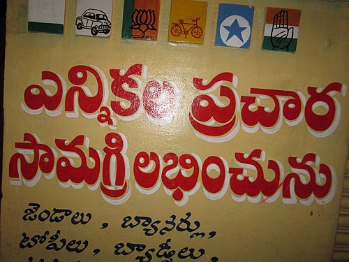 Wall painting at a shop in Telangana, India. It first shows the painted party symbols of all the major political parties in the region during the nationwide elections in India in 2014. It also has a Telugu inscription pointing to the availability of political flags, banners, caps, badges and other election material.