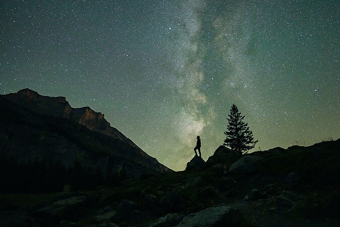 图为与银河成一直线的人正在英仙座流星雨下寻找流星，摄于瑞士的厄希嫩湖。
