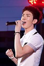 Jo Kwon, wearing a white collared shirt, belts into a microphone.