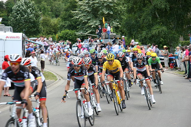 The peloton passing through Hotton, Belgium, in the first stage. Fabian Cancellara (RadioShack–Nissan) can be seen wearing the race leader's yellow je