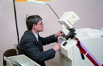 An analog printer minilab receiving film. No computer is present, and the film "scanner" is mounted on and integrated with the minilab so it can not be moved separately to somewhere else and connected through cables, the "scanner" is actually an optical enlarger, however there are digital minilabs with integrated scanners Ac-dyma-a-m-1997-minilab.jpg