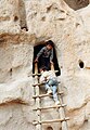 Children climb a ladder to explore the cave rooms at Bandelier National Monument, New Mexico