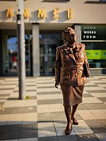 Das Bild zeigt die Bronzestatue zu Dr. Elisabeth Selbert, die mit Blazer und Akten unter dem Arm geht und dabei den Kopf nach rechts geneigt hat.