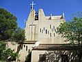 Église Saint-Benoît ; croix, clocher-mur moellons de béton et vitraux « meurtrières » ; aile « Est » de transept ouvrable sur cour pour les messes en haute saison touristique.