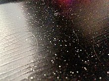 Dandruff with shed hair can be symptomatic of dry skin (shed skin scales and hairs on a dark wooden tabletop) Dandruff with Hair.jpg