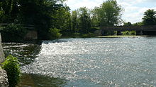 Weir pool with bridge. There is a clear Hydraulic jump visible as the water exits the weir slope and enters the pool. Dobbsweirwavejan2006.jpg