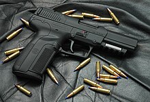 All-black FN Five-seveN USG pistol surrounded by twenty FN 5.7x28mm cartridges--the contents of a standard magazine. FN5701.jpg