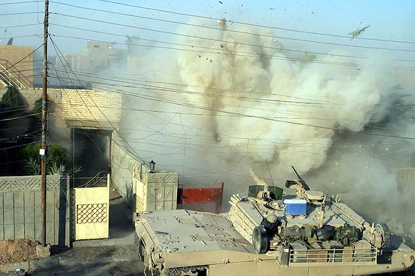 An M1 Abrams fires its main gun into a building to provide suppressive counterfire against insurgents.