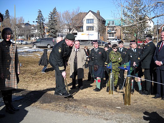 Groundbreaking ceremony on March 6, 2010. Colonel Thomas Putt, commander of 41 Canadian Brigade Group, breaks ground with a military entrenching tool. At left is City Councillor Druh Farrell, in whose ward the proposed monument was to be located. Visible in the photo are soldiers and veterans of the King's Own Calgary Regiment and The Calgary Highlanders. At centre is the commanding officer of the Highlanders, Lieutenant-Colonel Mike Vernon. Groundbreaking ceremony for Calgary Soldiers' Memorial on March 6, 2010.jpg