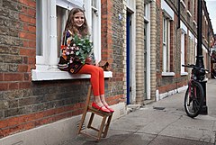 A girl sitting in a windowsill holding a bouquet. Columbia Market, London, UK