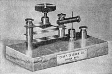 Precision crystal detector with iron pyrite crystal, used in commercial wireless stations, 1914. The crystal is inside the metal capsule under the vertical needle (right). The leaf springs and thumbscrew allow fine adjustment of the pressure of the needle on the crystal. Precision cat's whisker detector.jpg