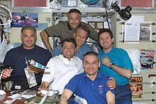 The STS-112 and Expedition 5 crewmembers share a meal in the Zvezda Service Module. STS-112 and Expedition 5 crew share a meal.jpg