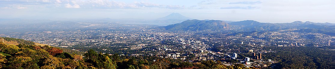 Panorámica del Área Metropolitana de San Salvador (ensin amosar una parte d'Antiguu Cuscatlán nin Santa Tecla, conceyos de La Llibertá que tamién formen parte del Gran San Salvador -derecha de la imaxe-).