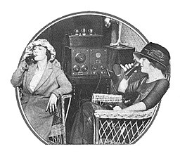 [Zwei Frauen trinken aus Gläsern während sie Radio hören.]