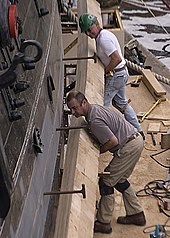 A plank used in the repair of a ship US Navy 090513-N-1060K-122 Ship restorers Chris Hanlon, bottom, and Paul Chiasson line up a new plank of white oak along USS Constitution's starboard side.jpg