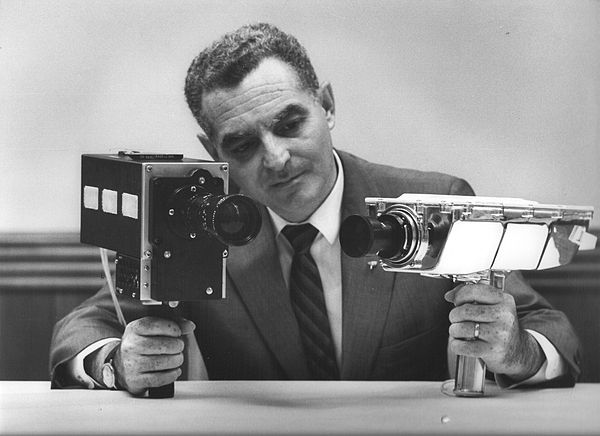 1969. Stan Lebar, the project manager for Westinghouse's Apollo Television Cameras, shows the Field-Sequential Color Camera on the left, and the Monochrome Lunar Surface Camera on the right. The Color camera was used on all flights starting with Apollo 10, while the monochrome Lunar Surface Camera was used on Apollo 11, and captured Neil Armstrong's first steps on the Moon.