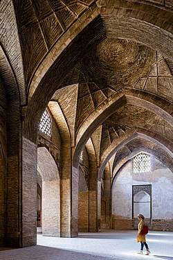 A woman tourist walking in the southwest corridor of Jameh mosque of Isfahan, Iran.