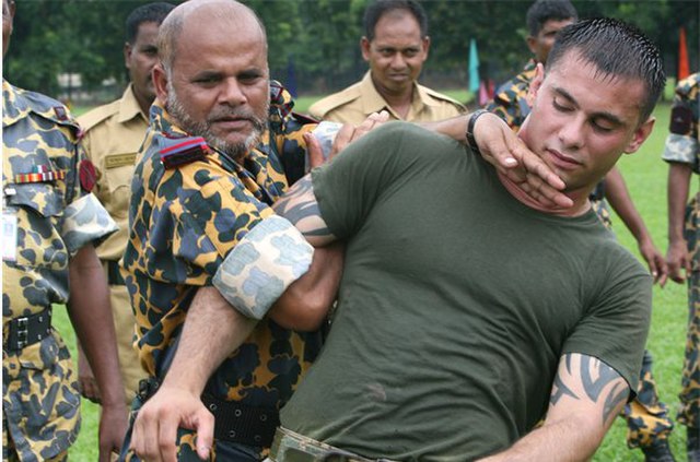 A Bangladesh Rifles Senior Warrant Officer (left in yellow/green outfit) applies a mechanical advantage control/hold to a United States Marine during 