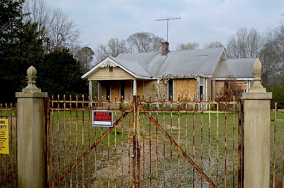 An old house with a rusting fence and a private property sign outside