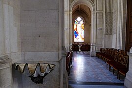 Le coquillage-bénitier et le vitrail de saint Arnoult à l'arrière-plan.