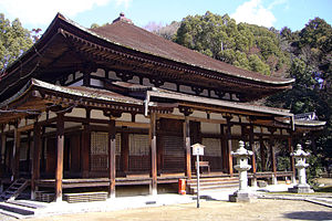 Wooden building with slightly raised floor, an open veranda and a pyramid shaped roof.