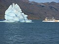 झील पर हिमशैल और पर्यटक नाव