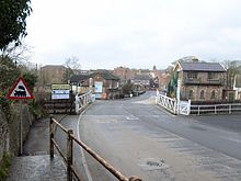 Looking into Bedale town from Aiskew across the level crossing. Bedale signal box is on the right and the bridge across Bedale Beck is just beyond the building centre left. The roadsign indicating a level crossing is incorrect – the barriers are clearly there!