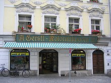 A colonial goods shop in Passau, 2005.
(The logo indicates that the shop is affiliated with Edeka.) Passau Residenzplatz Kolonialwaren.jpg