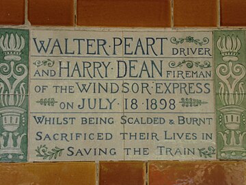 A tablet formed of two large tiles, bordered by green flowers in the style of the Arts and Crafts movement