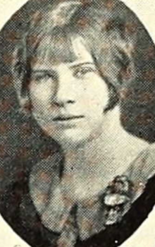 A young white woman with her hair cut in a bob with bangs, wearing a round-collared dress or blouse