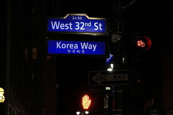 The Korea Way sign illuminated at night, with Hangul translation