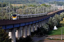 High-speed line on a viaduct to avoid ramp and road-crossing, with a British Rail Class 373 from Eurostar in old livery crossing it. Viaduc de la Haute-Colme 01 09.jpg