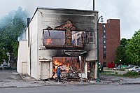 A burning building after a night of rioting in Minneapolis in 2020. A man walks by a burning building on Thursday morning after a night of protests and rioting in Minneapolis, Minnesota (49945327763).jpg