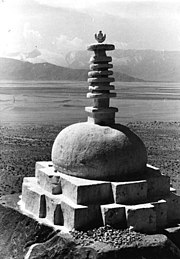 Photographie en noir et blanc d'un monumenen pierres surmonté d'une colonne composée de disques circulaires.