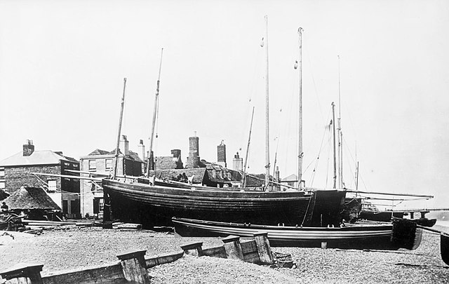 Deal luggers and a 4-oared galley on the beach at Port Arms station in 1866. The luggers are hauled up close to their capstans, where they are held by