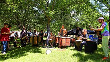 A drum circle at the 2023 Eeyore's Birthday Party. Drum circles at the festival range in size from a handful of participants to circles with hundreds of drummers and dancers. Drummers bring a wide variety of instruments from hand drums to kettledrums. Drum Circle Eeyores Birthday Austin Texas 2023.jpg