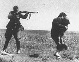 Член айнзацгруппы расстреливает еврейских женщину и ребёнка, близ Ивангорода, Украина, 1942 год. Фрагмент фотографии айнзацгруппы в Ивангороде
