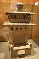 A ceramic model of a grain storehouse tower with windows and a balcony placed several stories up from the courtyard