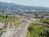 旧跨線橋から七飯方面と、その向こう側で建設中の函館新幹線総合車両所を俯瞰する。右側から新幹線本線、新ルート切り替え後の在来線線路（左下が現在の4番線）、使用停止となった在来線旧線路。