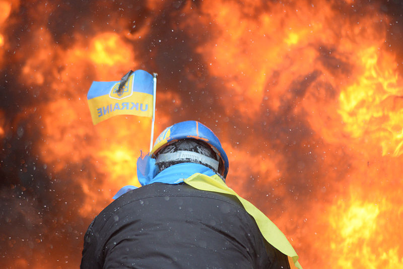 File:Protester wearing Ukraine state flag colors facing the massive fire set by protesters to prevent internal forces from crossing the barricade line. Kyiv, Ukraine. Jan 22, 2014.jpg