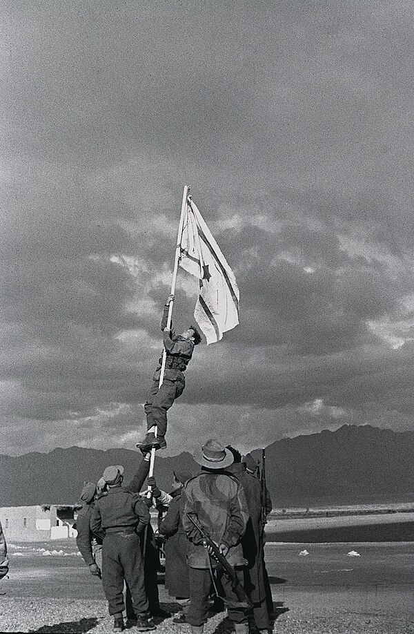 Captain Avraham "Bren" Adan raising the Ink Flag at Umm Rashrash, a site now in Eilat, marking the end of the war.