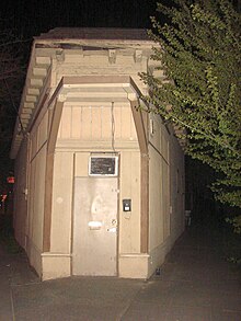 photo de la porte d'entrée d'un bâtiment faisant l'angle de deux rues dans la nuit.