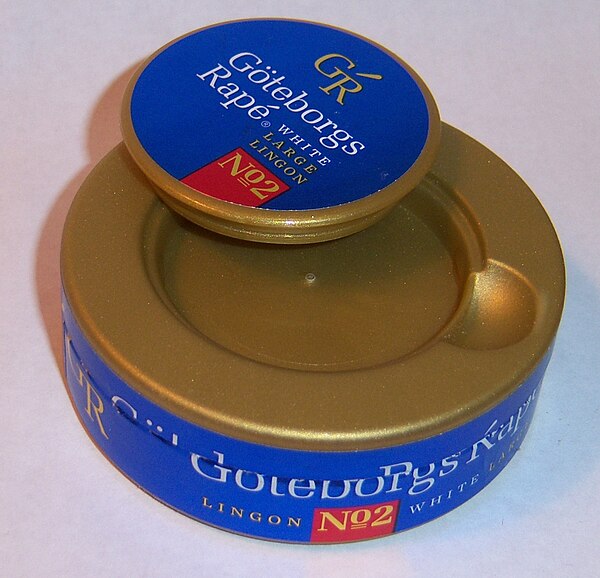 Catch lid found on many snus tins, which snaps in and out of place. The small compartment is typically used for the temporary storage of used snus por